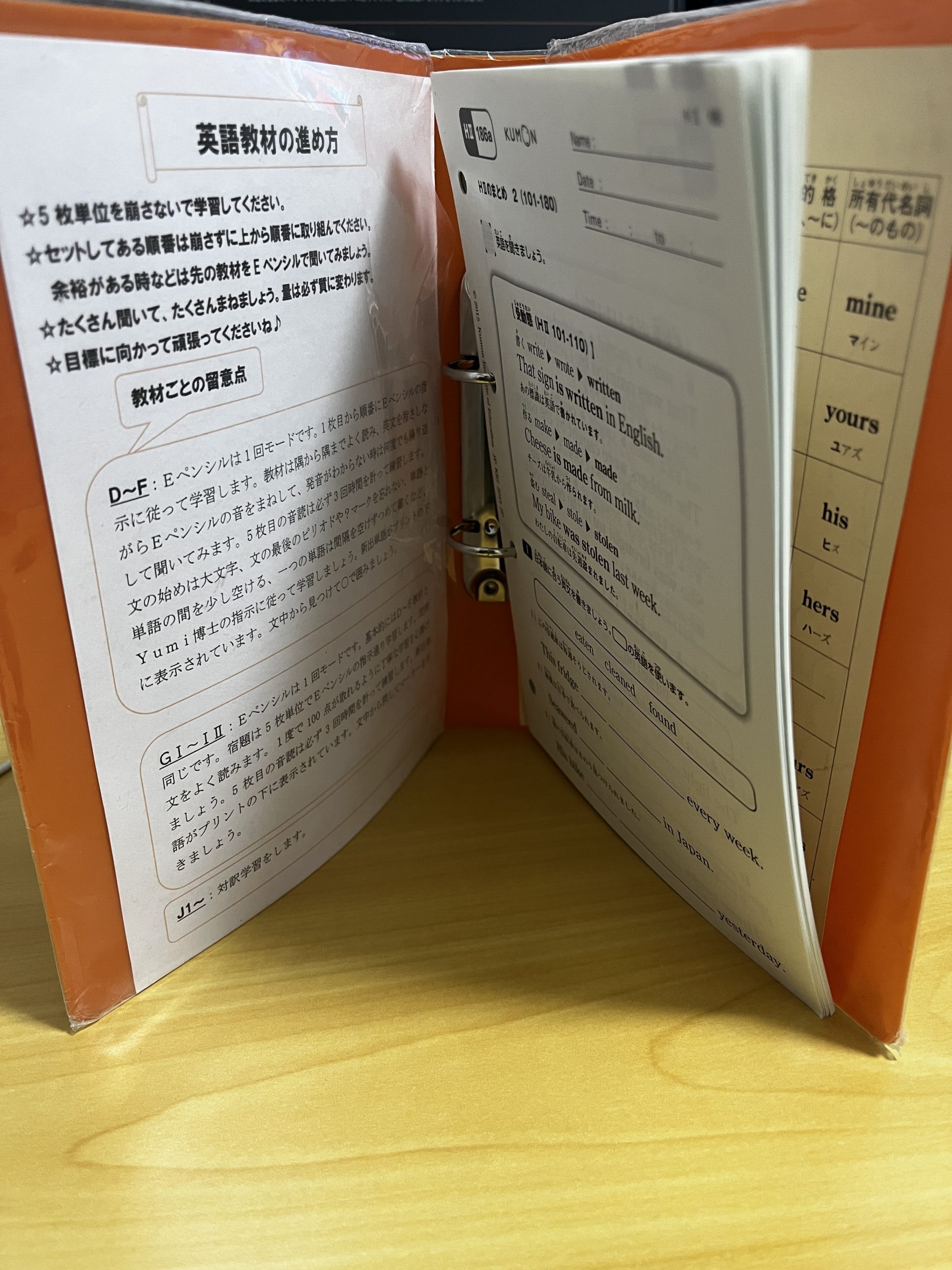 わが家で使っている公文のオレンジのバインダー。HⅡ186aのプリントの束と「英語教材の進め方」の紙が挟まっています。